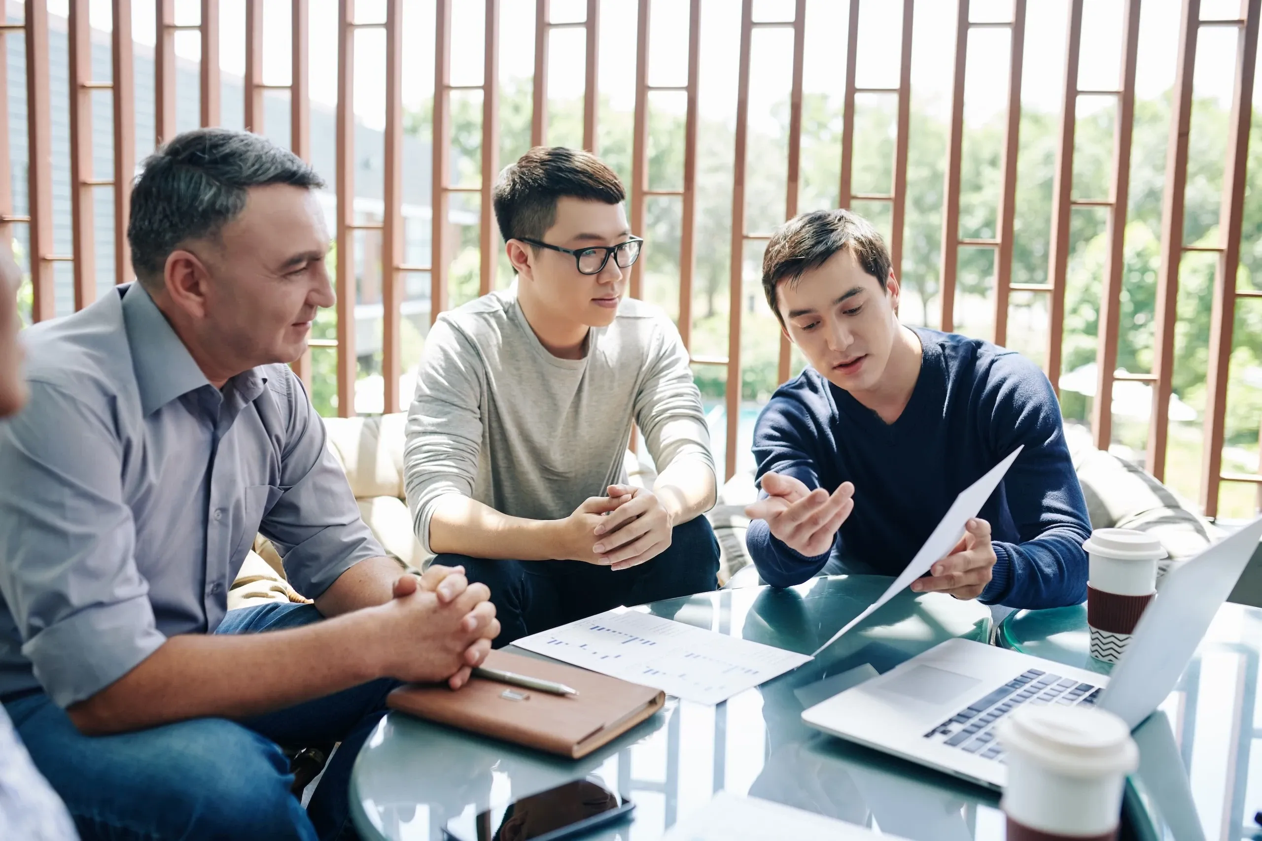 Team leader échangeant avec deux membres de son équipe autour d’un document
